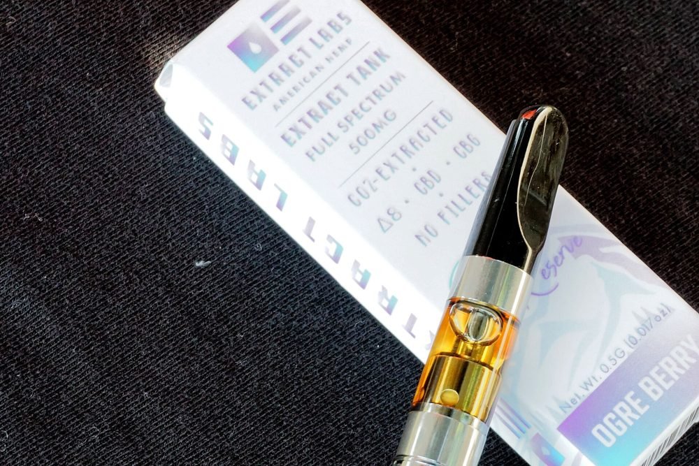 Schachtel mit der Aufschrift „Terpen-infundiertes Destillat“ neben einer Vape-Kartusche, die zeigt, wie Destillatkartuschen nach der Raffinierung aromatisiert werden